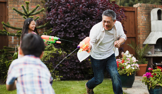 A family playing with water pistols in a yard