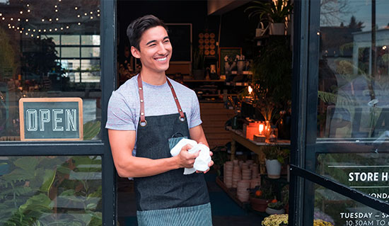 Man standing outside of shop next to open sign