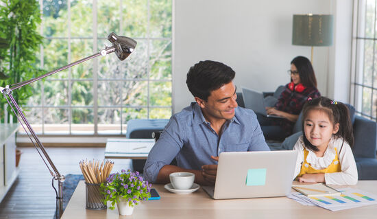 A family in a bright living room using laptop computers